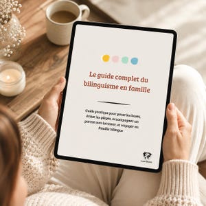 May include: A digital tablet displaying a document titled Le guide complet du bilinguisme en famille. The screen features four colored circles at the top, a black horizontal line, and text in French, with a small Word Bridge logo at the bottom.