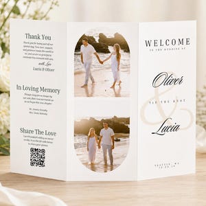 Może przedstawiać: Biały, potrójnie składany program ślubny ze zdjęciami pary na plaży. Program zawiera tekst "Witamy", "Oliver & Lucia" i "Tie the Knot". Widoczny jest również kod QR.