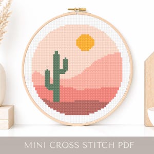 May include: A cross-stitch design in a wooden hoop features a desert landscape with a green cactus, a yellow sun, and pink and peach-colored mountains. The text "MINI CROSS STITCH PDF" is at the bottom.