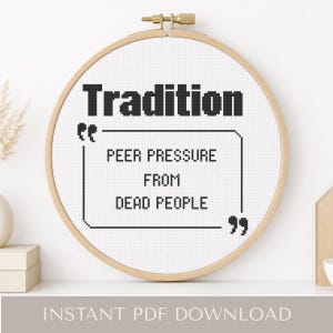 May include: A cross-stitch embroidery hoop with the word "Tradition" above a quote: "Peer pressure from dead people." The text is in black on a white background. The wooden hoop has a brass screw.