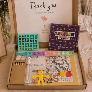 May include: A gift box filled with games and toys, including a Tangram puzzle, a Connect 4 game, a pop-it toy, a game board, and a yellow figure. The box has a message that says "Thank you" for a special day.