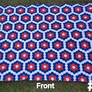 May include: A large, rectangular blanket with a repeating geometric pattern of white, red, and blue hexagonal shapes. The blanket is spread out on green grass. The word "Front" and the number "5" are visible.