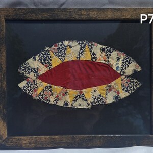 Puede incluir: Obra de arte textil enmarcada. Presenta una forma ovalada roja central rodeada de tela estampada en amarillo, azul marino y crema. Enmarcada en un marco de madera marrón oscuro, con el texto "P7" en la esquina superior derecha.