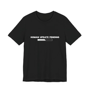 Può includere: T-shirt nero con la scritta bianca "HUMAN UPDATE PENDING" e una barra di avanzamento bianca. La maglietta è a girocollo ed è adatta per l'uso quotidiano.