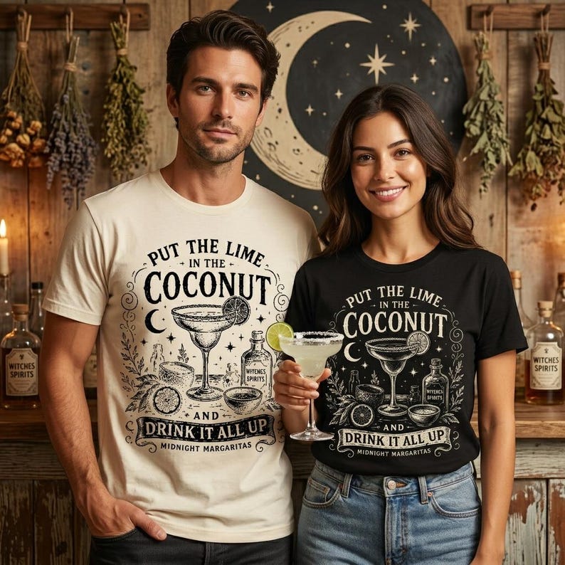 May include: A cream-coloured t-shirt and a black t-shirt, both featuring a graphic print of a margarita glass, a lime slice, and the text "PUT THE LIME IN THE COCONUT AND DRINK IT ALL UP MIDNIGHT MARGARITAS" in a decorative black font.