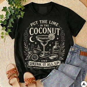 May include: A black short-sleeved t-shirt featuring a white graphic print of a margarita glass, a bottle labelled Witches Spirits, and the text Put the lime in the coconut and drink it all up Midnight Margaritas with stars and moon accents.