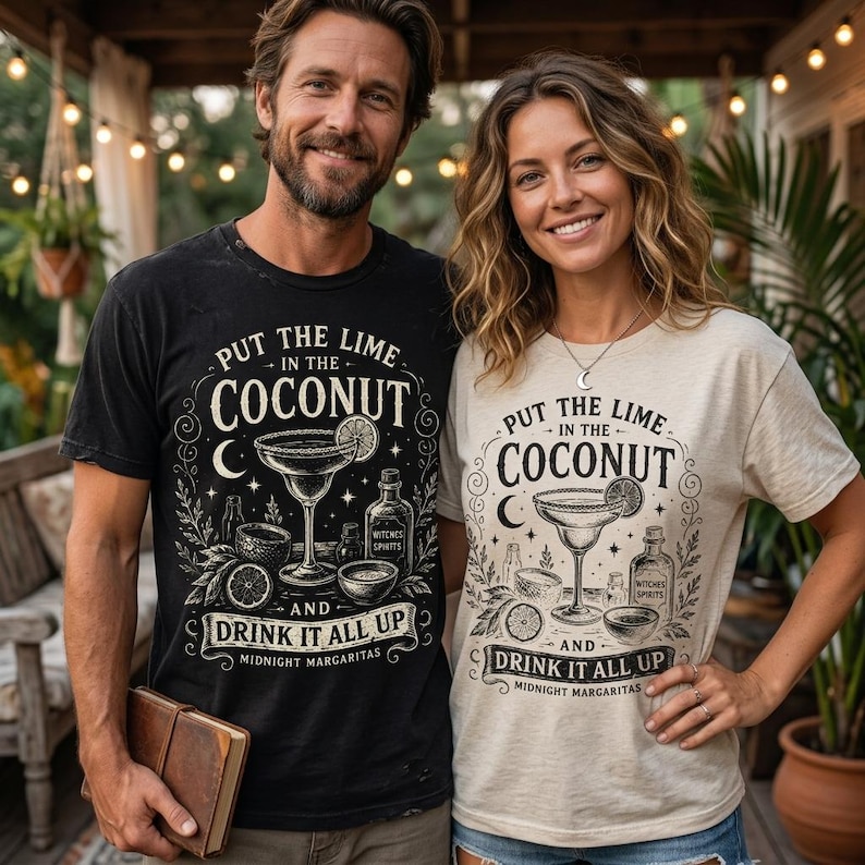 May include: A black t-shirt and a beige t-shirt, both featuring a graphic print of a margarita glass, a bottle labelled Witches Spirits, and the text Put the Lime in the Coconut and Drink it All Up Midnight Margaritas with decorative flourishes.