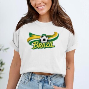 White t-shirt with Brazil soccer logo featuring a soccer ball and wavy flag colors.
