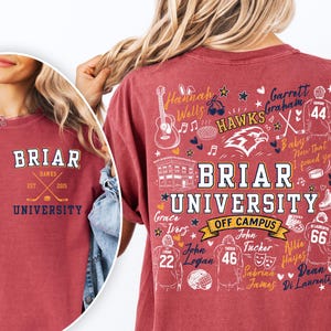 May include: A maroon t-shirt featuring a small Briar University logo on the front left chest. The back displays a large graphic with the text Briar University Off Campus, surrounded by hockey-themed illustrations, names, and jersey numbers.