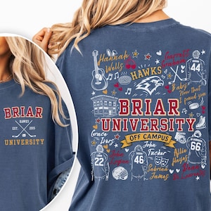 May include: A blue t-shirt featuring Briar University graphics. The front displays Briar University Hawks Est. 2015 with crossed hockey sticks. The back features Briar University Off Campus text, hockey jerseys, names, and various icons.