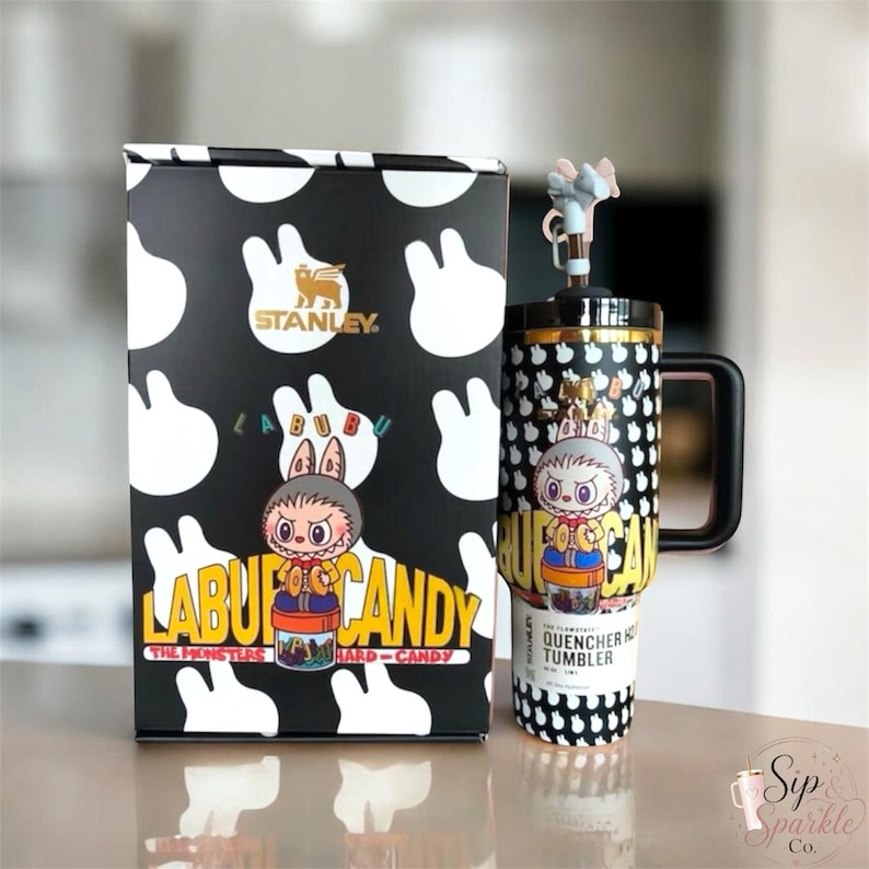 May include: A black and white Stanley Labubu The Monsters hard candy tumbler with a matching box. The tumbler features a character graphic, a black handle, and a lid with a small character topper. The box displays the Stanley logo and Labubu text.