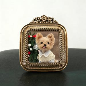 Può includere: Un ritratto incorniciato di uno Yorkshire Terrier con occhiali e un maglione, con un piccolo albero di Natale sullo sfondo. La cornice è dorata con dettagli ornati. Il cane ha la lingua di fuori.