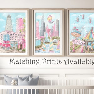 May include: Three watercolor paintings in light blue frames depicting scenes from Chicago. The first painting shows the Water Tower Place building, the second shows the Chicago skyline with a hot air balloon, and the third shows Navy Pier with a Ferris wheel and carousel.