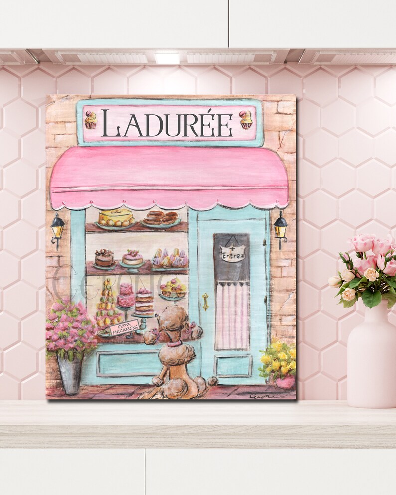 May include: A painting of a pink and blue storefront with the name "LADUR&Eacute;E" above the entrance. The storefront has a display of pastries in the window and a sign that says "PETITS MACARONS". A brown poodle is standing in front of the store looking at the pastries.