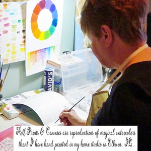 May include: A woman paints in her home studio. The image includes a color wheel, paint tubes, and a handwritten note that reads "All Prints & Canvases are reproductions of original watercolors that I have hand painted in my home studio in Elburn, IL."