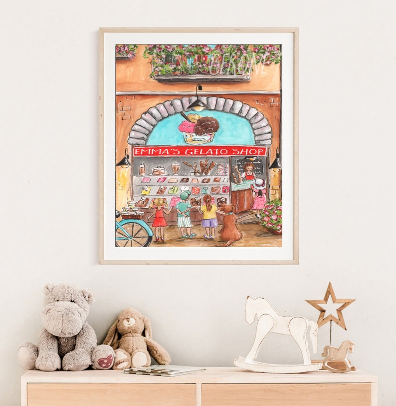 Op de afbeelding: Een aquarel van een gelatowinkel met een bord waarop "Emma's Gelato Shop" staat. Er staan kinderen voor de winkel en een hond zit op de stoep.