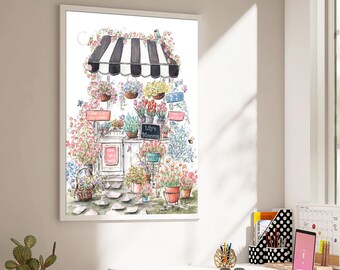 May include: A framed watercolor print depicting a flower shop with a black and white striped awning. The shop features various potted flowers, a stone path, and a chalkboard sign that reads Lily's Blooms, surrounded by climbing floral vines.