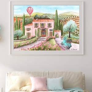 K&ouml;nnte beinhalten: Ein gerahmtes Aquarellbild, das eine rosa Villa in einer h&uuml;geligen Landschaft zeigt, mit einem rot-wei&szlig;en Hei&szlig;luftballon am Himmel, gr&uuml;nen Zypressen, einem blauen Roller mit Blumen im Vordergrund und dem Wort Italia auf einer Mauer.