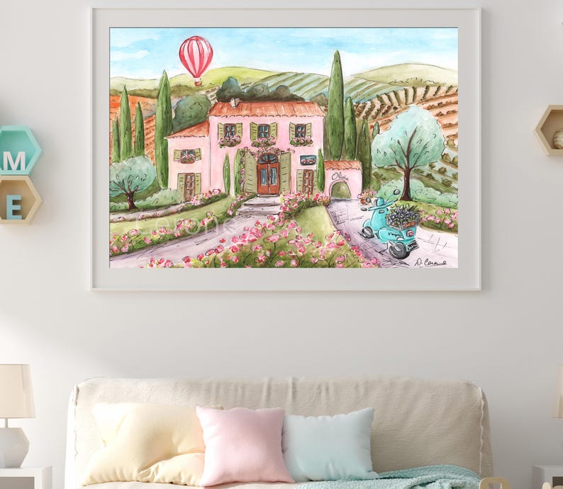K&ouml;nnte beinhalten: Ein gerahmtes Aquarellbild, das eine rosa Villa in einer h&uuml;geligen Landschaft zeigt, mit einem rot-wei&szlig;en Hei&szlig;luftballon am Himmel, gr&uuml;nen Zypressen, einem blauen Roller mit Blumen im Vordergrund und dem Wort Italia auf einer Mauer.