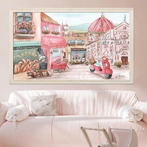 K&ouml;nnte beinhalten: Ein gerahmter Druck im Aquarellstil, der eine europ&auml;ische Stra&szlig;enszene mit einer rosa B&auml;ckerei, einem Caf&eacute; mit Sitzgelegenheiten im Freien, einem roten Roller und einer gro&szlig;en Kathedrale mit Kuppel im Hintergrund zeigt. Das Bild hat sanfte Pastellt&ouml;ne.