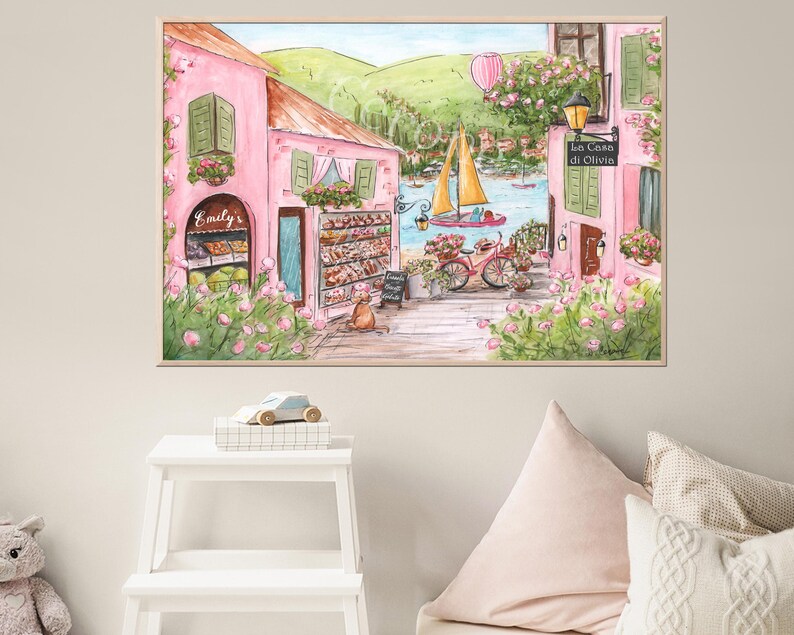 Pode incluir: Uma pintura em aquarela de um pr&eacute;dio rosa com uma placa que diz "Emily's". O pr&eacute;dio est&aacute; localizado em uma rua com uma bicicleta e um barco ao fundo. A pintura est&aacute; emoldurada em uma moldura marrom clara.