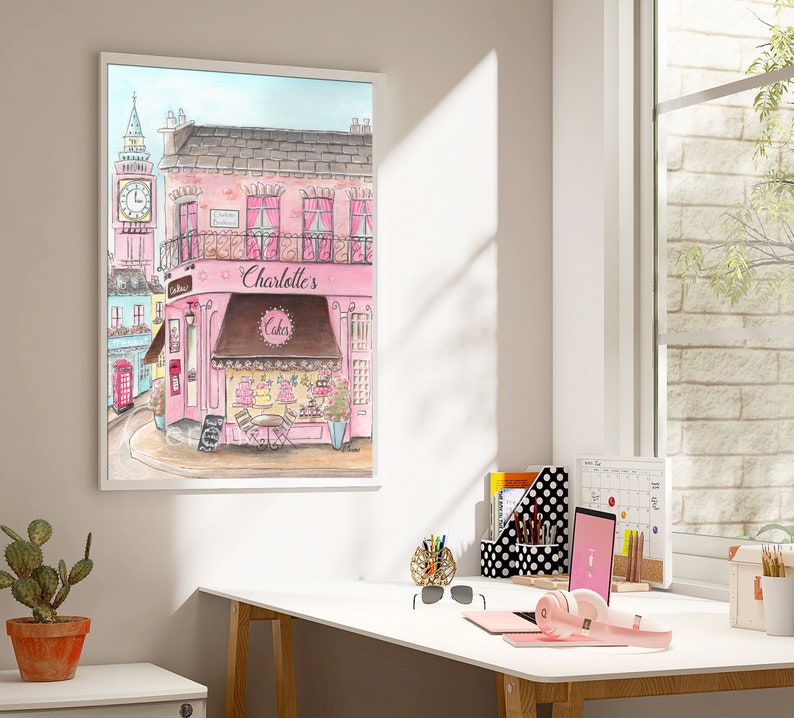 May include: A watercolor painting of a pink building with a brown awning that says "Charlotte's Cakes". The building is on a street with a red telephone booth and a clock tower in the background.