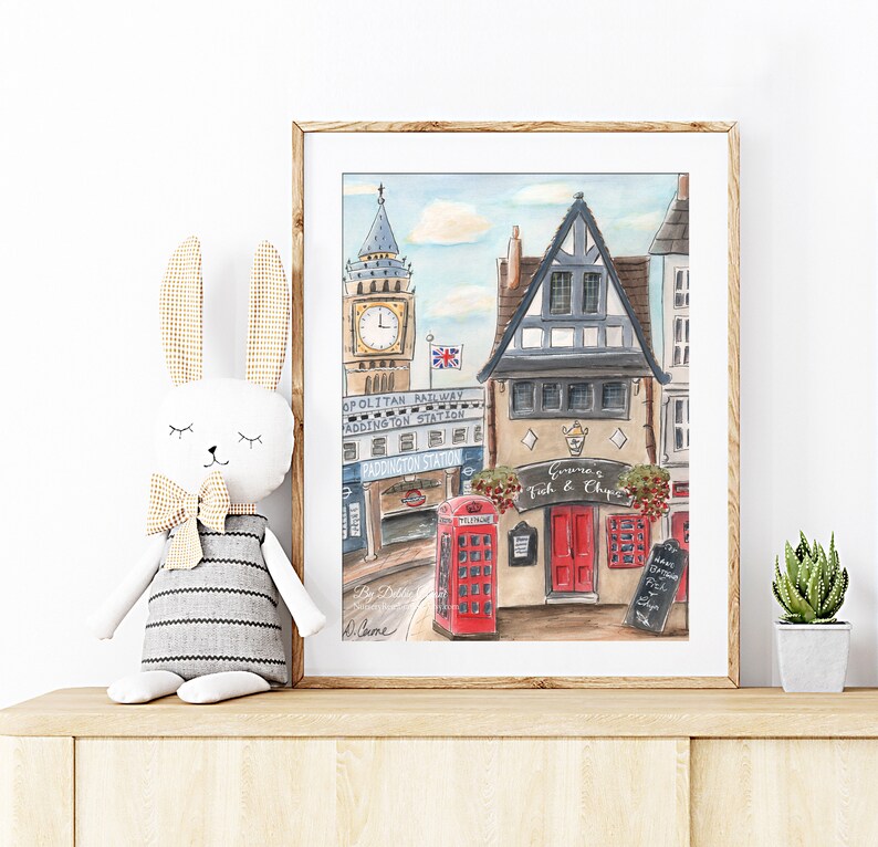 Puede incluir: Una pintura de acuarela de una escena callejera de Londres con una cabina telef&oacute;nica roja, un edificio con un letrero que dice "Gemma's Fish & Chips", y Big Ben en el fondo.