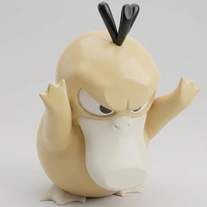 Può includere: Statuetta di Psyduck color beige chiaro con becco e piedi bianchi e capelli neri. La statuetta ha un'espressione arrabbiata con le braccia alzate. La statuetta è un oggetto da collezione.