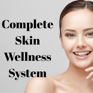 May include: A smiling individual with clear skin and dark hair pulled back, positioned next to the bold black text that reads Complete Skin Wellness System. The subject has a neutral expression and is shown from the shoulders up against a light background.