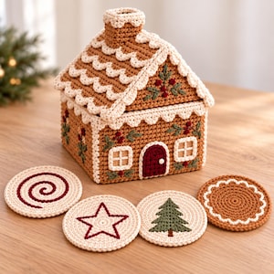 May include: A crochet gingerbread house box with a removable roof, featuring cream-colored scalloped trim, embroidered holly, and a dark red door. Four round crochet coasters are included, displaying a red spiral, a red star, a green tree, and a brown scalloped pattern.