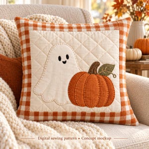 Puede incluir: Un cojín cuadrado acolchado con un panel central color crema, que presenta un fantasma blanco y una calabaza naranja con una hoja verde en aplique. El cojín está bordeado por un diseño de cuadros vichy naranja y blanco. Texto: Digital sewing pattern • Concept mockup.