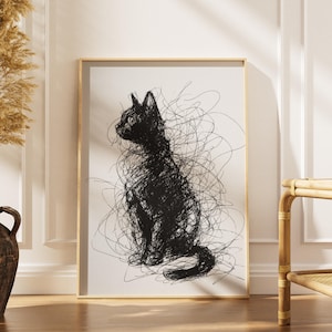 May include: A framed art print featuring a black cat silhouette created with expressive, scribbled lines. The artwork is set against a white background, framed in a light wood. The cat is depicted in a seated position, with its tail curled.