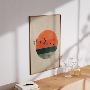 May include: A framed art print featuring a minimalist design of a sunset with birds in flight. The artwork showcases an orange sun, a green and blue horizon, and a flock of birds against a neutral background. The frame is a warm brown.