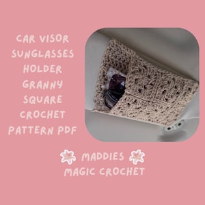 May include: A beige granny square crochet sunglasses holder attached to a car visor. The holder contains two pairs of sunglasses. Text on the image reads "CAR VISOR SUNGLASSES HOLDER GRANNY SQUARE CROCHET PATTERN PDF" and "MADDIES MAGIC CROCHET".