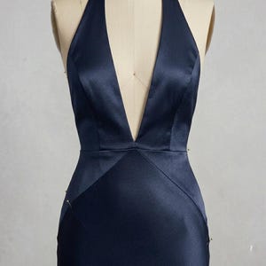 Close-up of the halter neckline and plunging V front on a navy satin evening gown. The minimalist design and premium satin fabric offer timeless elegance.