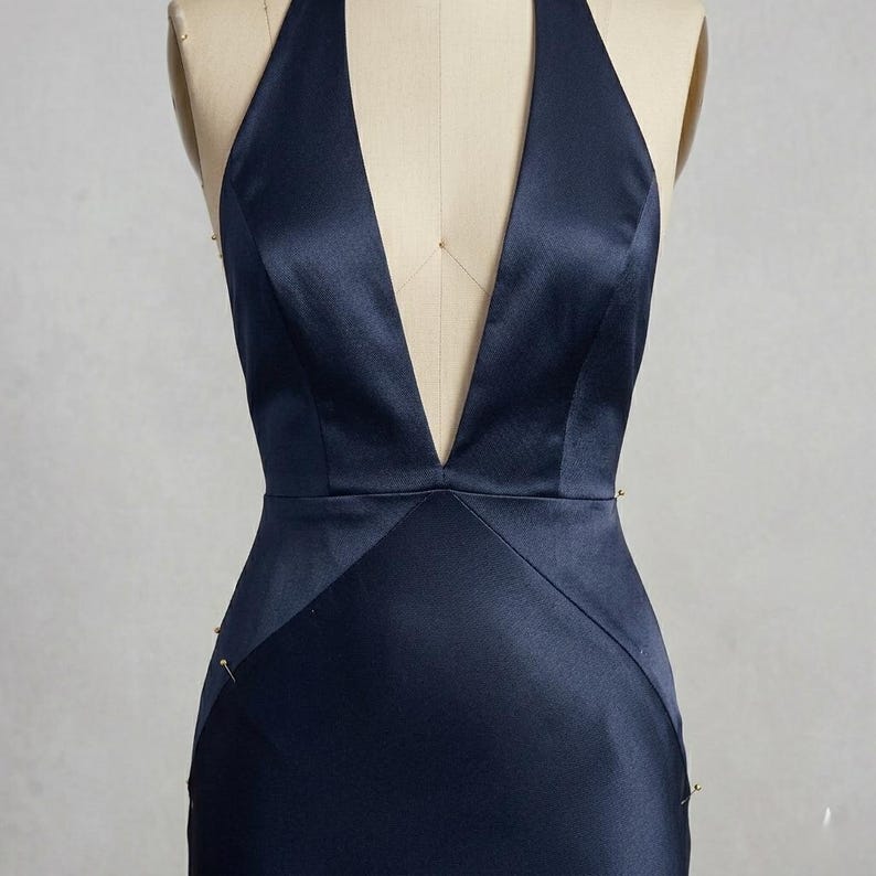Close-up of the halter neckline and plunging V front on a navy satin evening gown. The minimalist design and premium satin fabric offer timeless elegance.
