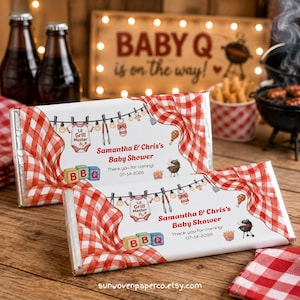 May include: Two rectangular chocolate bar wrappers featuring a red and white gingham pattern. The design includes a clothesline with a baby onesie labeled Lil Grill Master, BBQ blocks, a grill, and text reading Samantha & Chris's Baby Shower 07-14-2026.