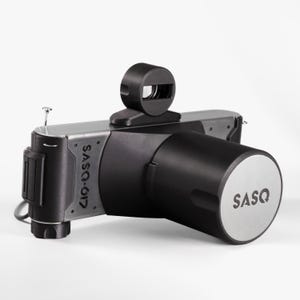 May include: A black and silver camera with the text "SASQ-617" and "SASQ" visible. The camera has a cylindrical lens and a viewfinder on top. The camera is on a white background.