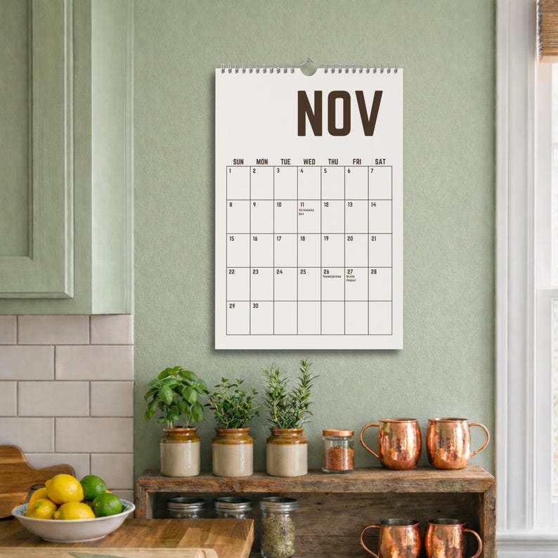 May include: A wall calendar for November with a simple design. The word "NOV" is at the top in dark brown letters. The calendar grid is black on a white background. The calendar is hanging on a light green wall.