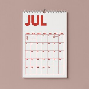 Pu&ograve; includere: Un calendario da parete che mostra il mese di luglio in grandi lettere rosse nella parte superiore. La griglia mostra i giorni della settimana da luned&igrave; a domenica, con date numerate da 1 a 31 in rosso. Il testo Independence Day &egrave; il 4 luglio.