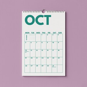 Pu&ograve; includere: Un calendario da parete bianco con testo e linee della griglia color verde acqua. La parte superiore mostra il mese come OCT in grandi lettere. La griglia del calendario mostra i giorni della settimana dal luned&igrave; alla domenica, numerati da 1 a 31.