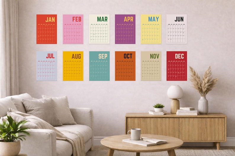 Pode incluir: Uma cole&ccedil;&atilde;o de doze calend&aacute;rios mensais coloridos, cada um com uma cor de fundo diferente e o nome do m&ecirc;s no topo. Os calend&aacute;rios s&atilde;o exibidos em uma parede em uma sala de estar, com m&oacute;veis e decora&ccedil;&atilde;o vis&iacute;veis.