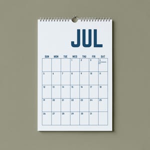 May include: A white spiral-bound calendar for July hangs against a neutral background. The word "JUL" is printed in bold, dark blue letters at the top. The calendar grid is outlined in dark blue, with dates and days of the week.