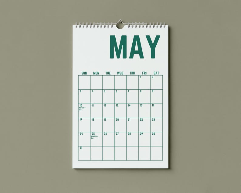 May include: A white spiral-bound calendar for the month of May, hanging against a neutral background. The word "MAY" is printed in bold, dark green letters at the top. The calendar grid is outlined in green, with dates and days of the week.