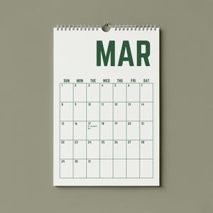 May include: A white spiral-bound calendar for the month of March, hanging against a muted green background. The word "MAR" is printed in bold, dark green letters at the top. The calendar grid is outlined in dark green, with dates and days of the week.