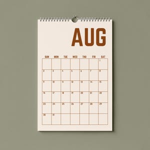 May include: A spiral-bound wall calendar for August, with a cream-colored background and brown text. The word "AUG" is at the top, with the days of the week and dates below. The calendar is hanging on a light green wall.