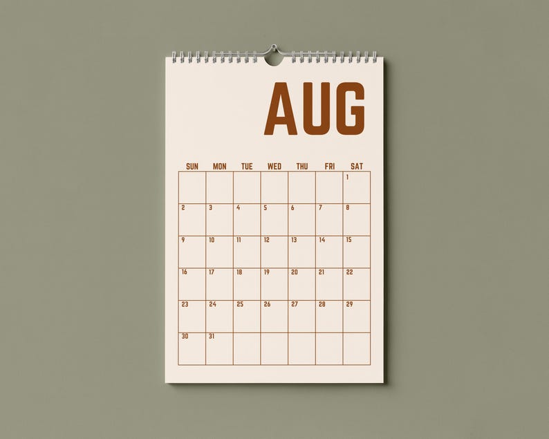 May include: A spiral-bound wall calendar for August, with a cream-colored background and brown text. The word "AUG" is at the top, with the days of the week and dates below. The calendar is hanging on a light green wall.