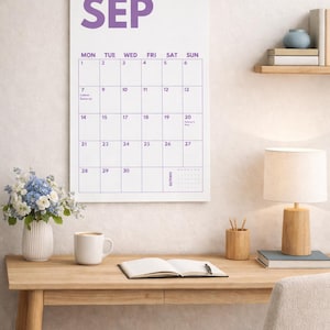 Pu&ograve; includere: Un calendario da parete per il mese di settembre con sfondo bianco, testo viola e una rilegatura a spirale metallica argentata nella parte superiore. La griglia mostra i giorni della settimana e le date, con un'anteprima di ottobre in basso a destra.