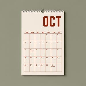 May include: A cream-colored wall calendar for October, with a spiral binding and a metal hook for hanging. The word "OCT" is printed in bold, dark red letters at the top. The calendar grid is outlined in dark red, with dates and days of the week.