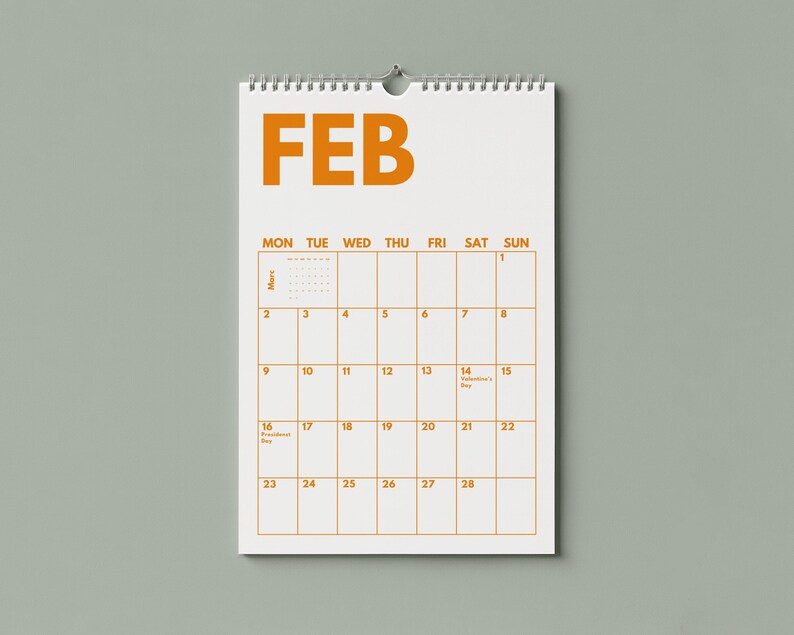 Pu&ograve; includere: Un calendario da parete per il mese di febbraio con sfondo bianco e testo arancione. Il calendario presenta una griglia con i giorni della settimana da luned&igrave; a domenica, date numerate da 1 a 28 e una rilegatura a spirale metallica in alto.